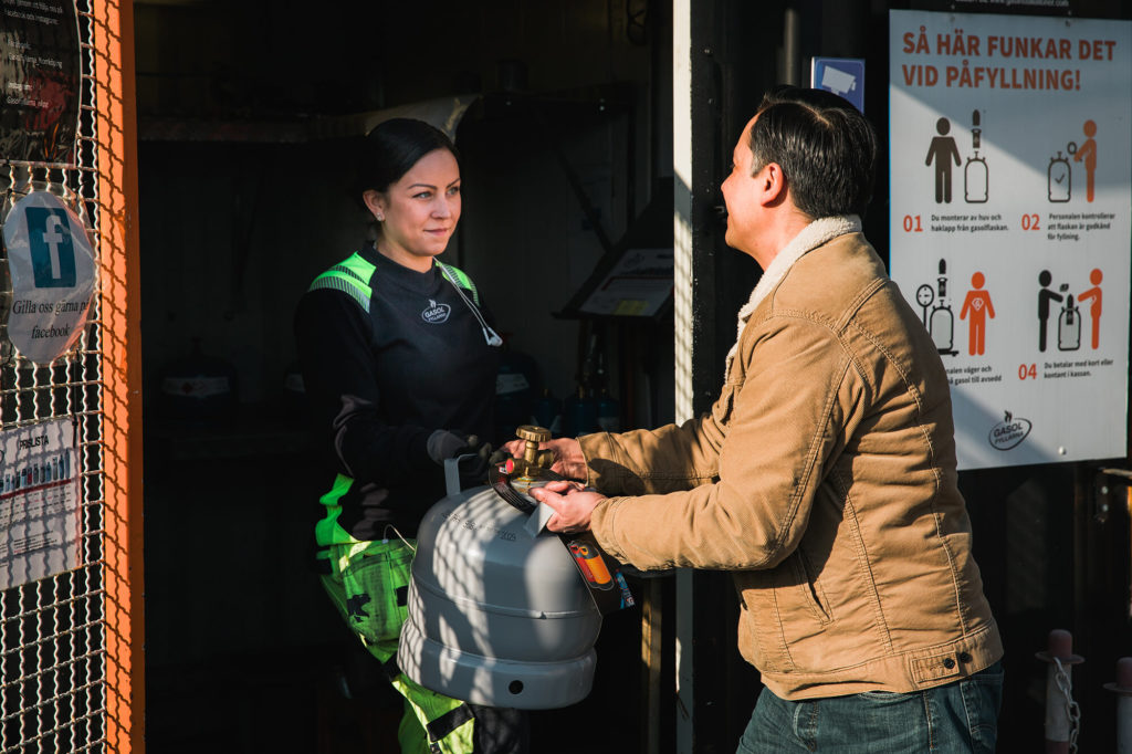 Kvinna ger en gasolflaska till en man